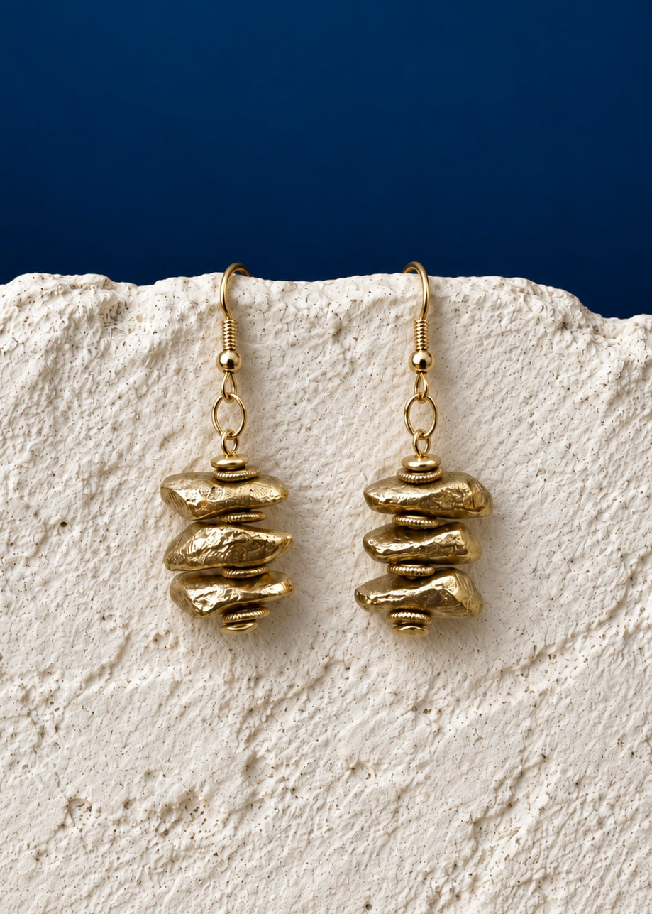 Golden Pebble Stack Earrings on white textured surface