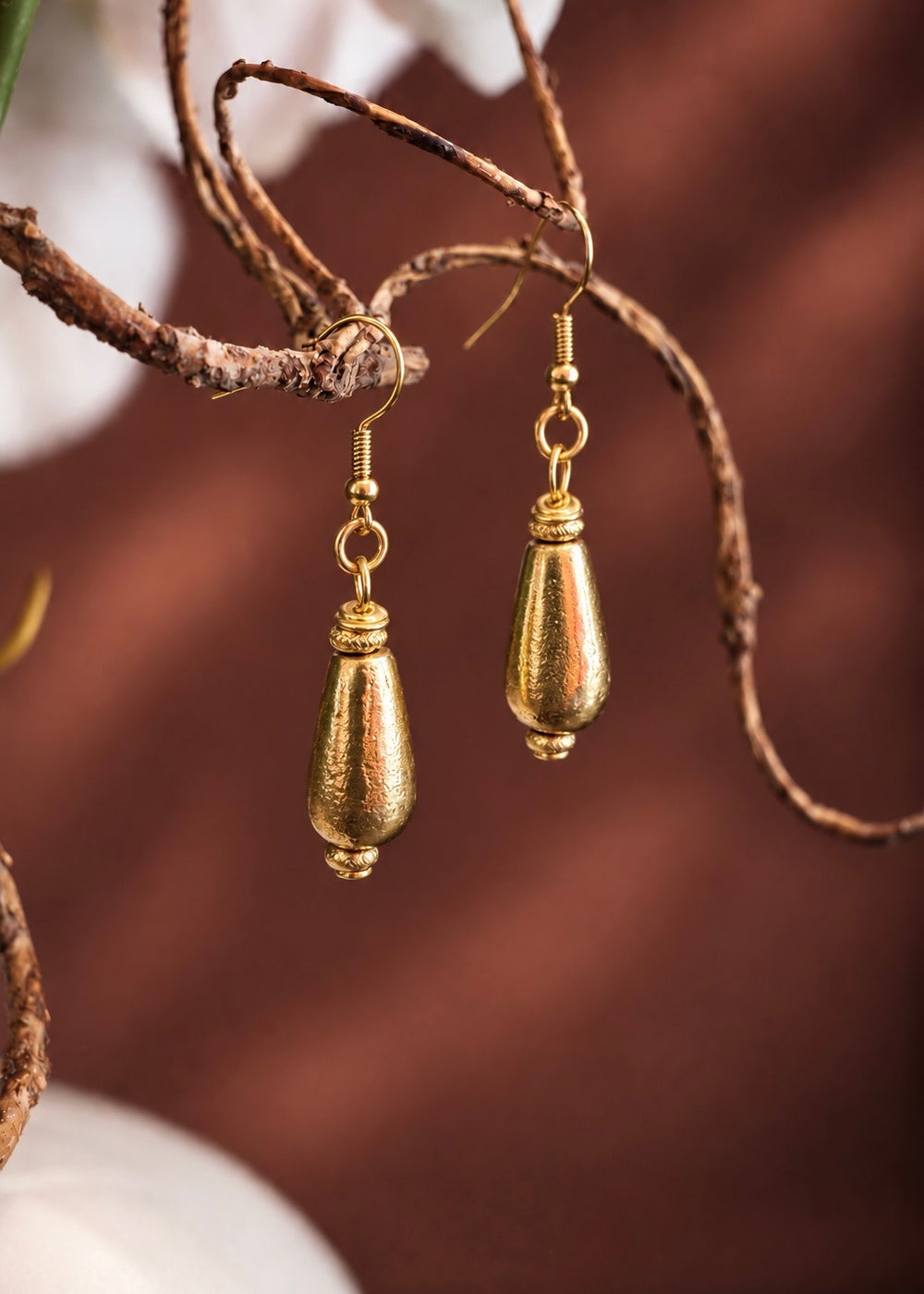 Golden Smooth Drop Earrings hanging from a branch