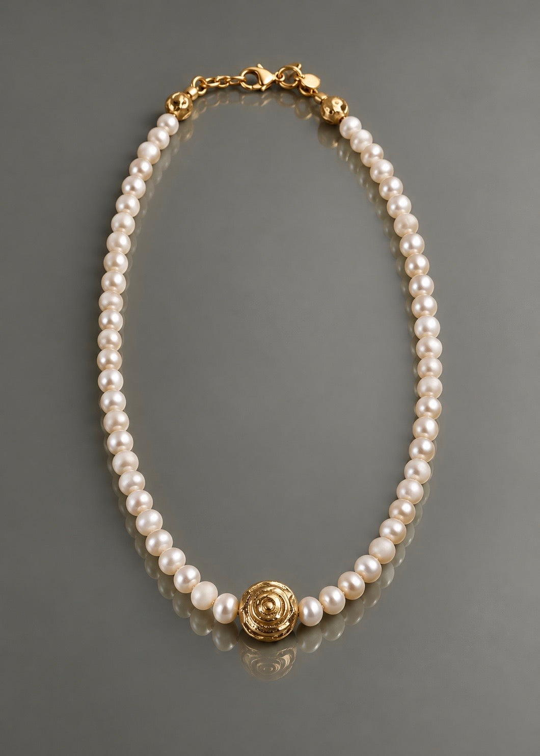 Full Circle freshwater pearl necklace with cast brass centerpiece on gray