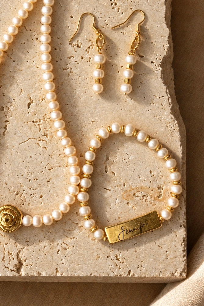 Yours Truly personalized pearl bracelet styled with a pearl necklace and earrings on stone