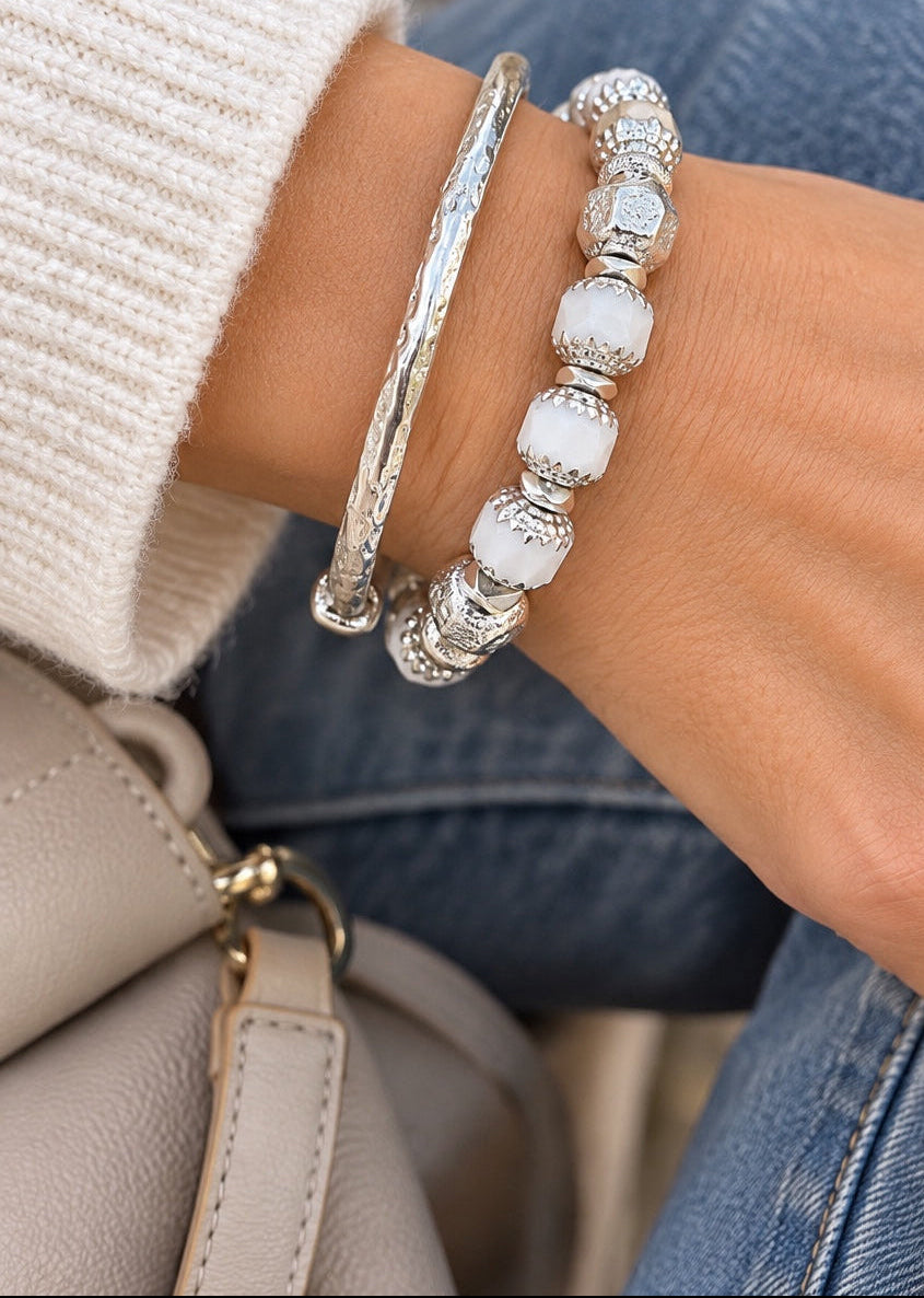 Cathedral White bracelet styled with a silver bangle on a wrist