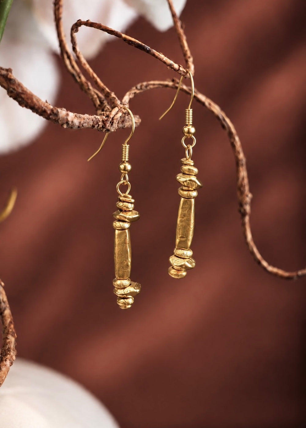 Golden Column Drop Earrings hanging from a branch