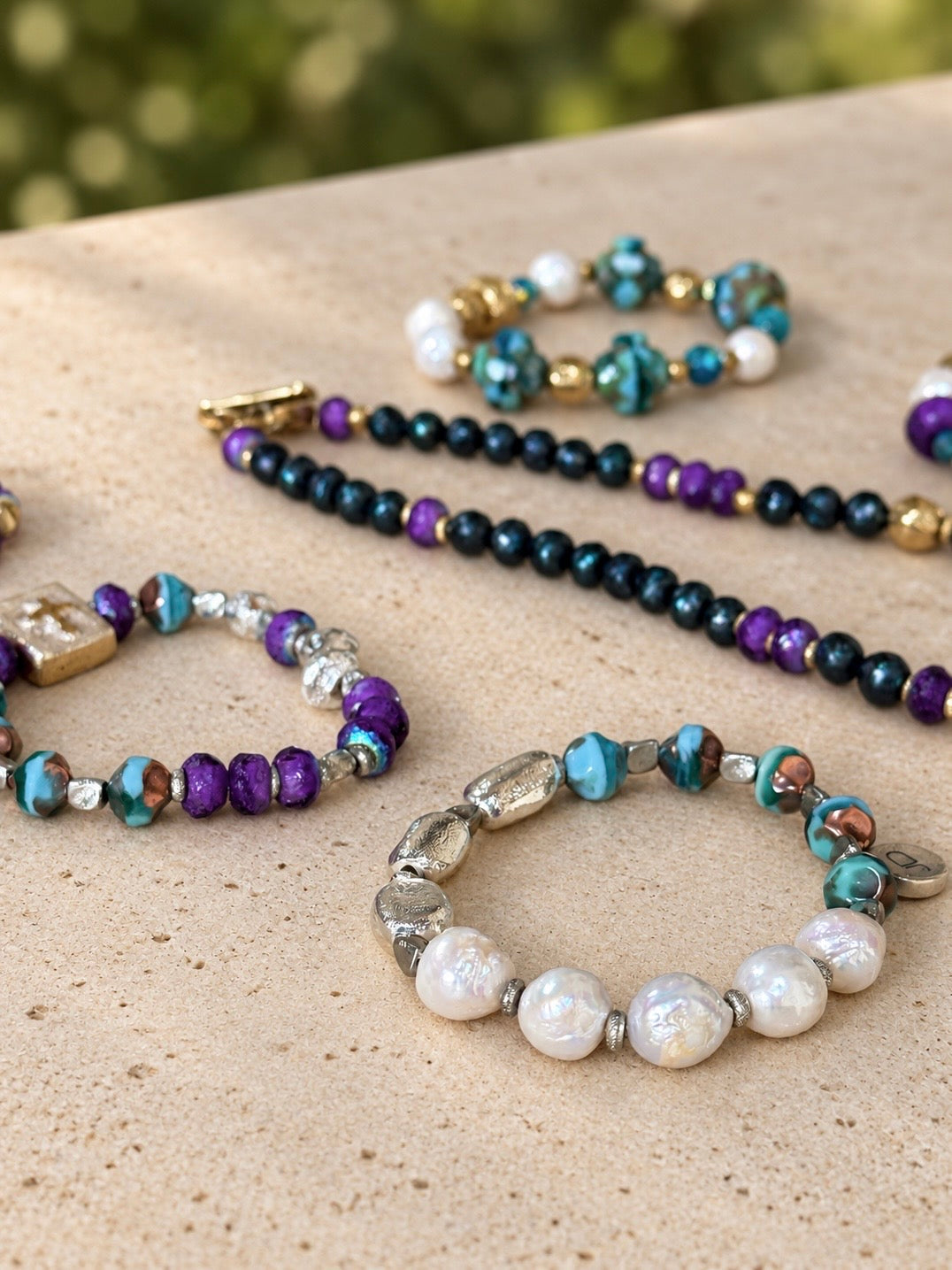 Gilded Garden bracelets and necklace styled on stone; pieces sold separately