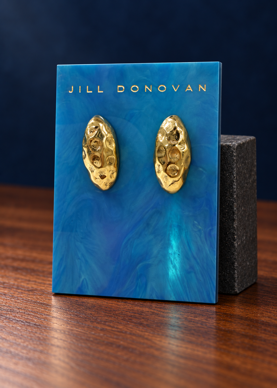 Golden Sculpted Oval Earrings — Only One Pair displayed on a lucite card