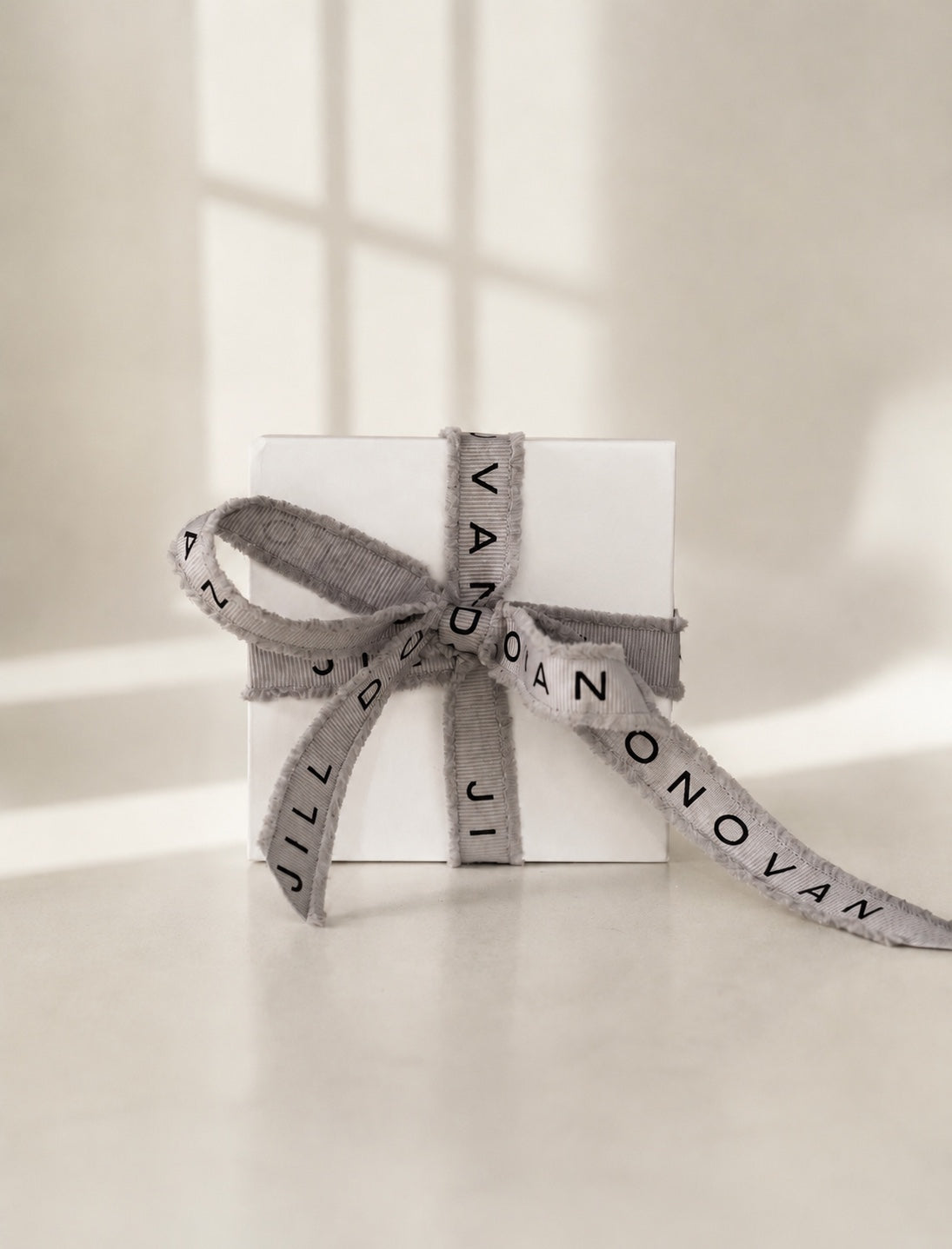 Signature Jill Donovan white gift box tied with gray Jill Donovan ribbon.