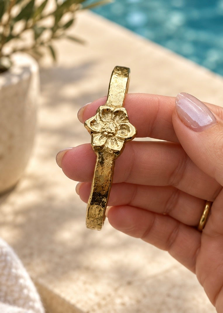 Gold Magnolia gift cuff held beside a pool.